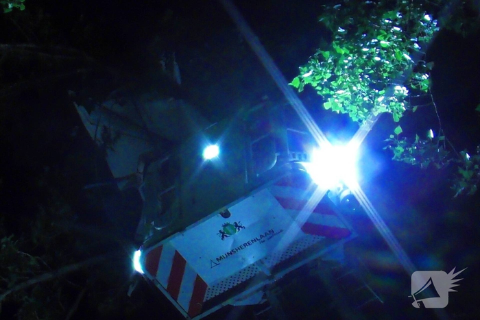 Brandweer haalt parasol uit boom met autoladder