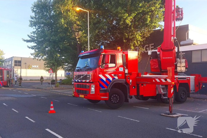 Brand in boom en bosschages naast bedrijfspand