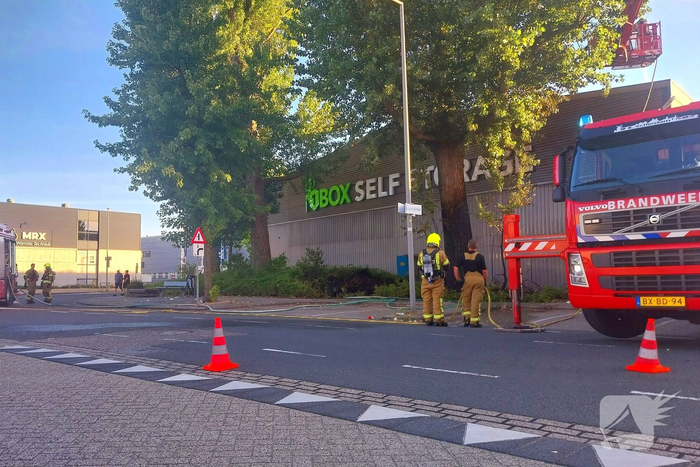 Brand in boom en bosschages naast bedrijfspand