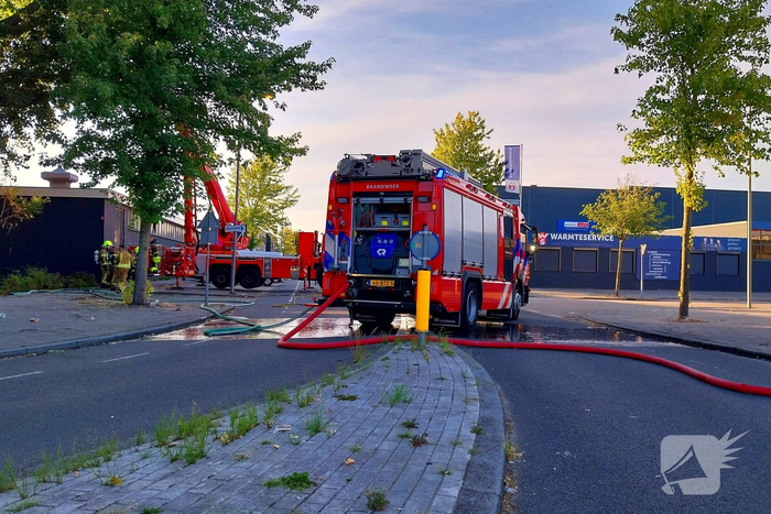 Brand in boom en bosschages naast bedrijfspand