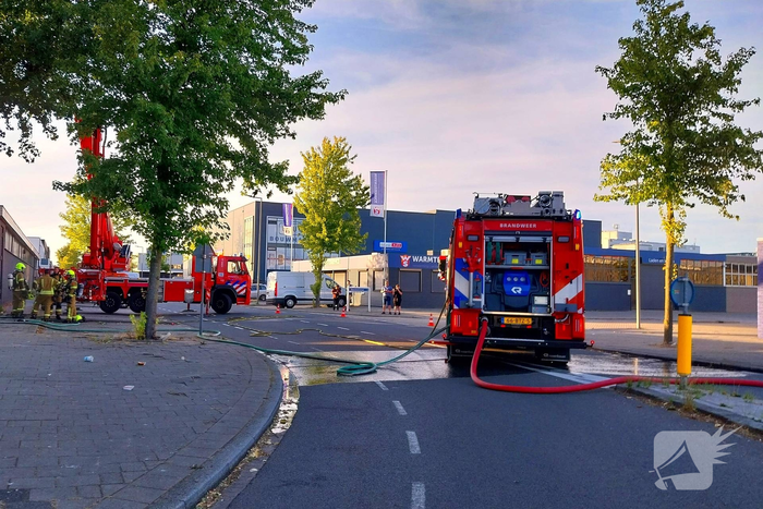 Brand in boom en bosschages naast bedrijfspand
