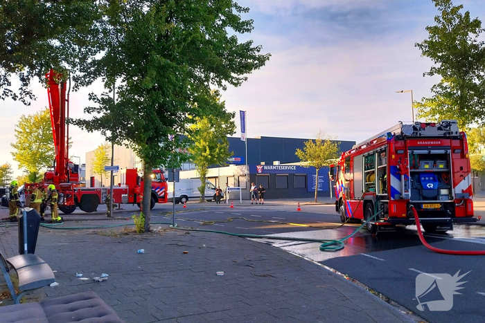 Brand in boom en bosschages naast bedrijfspand