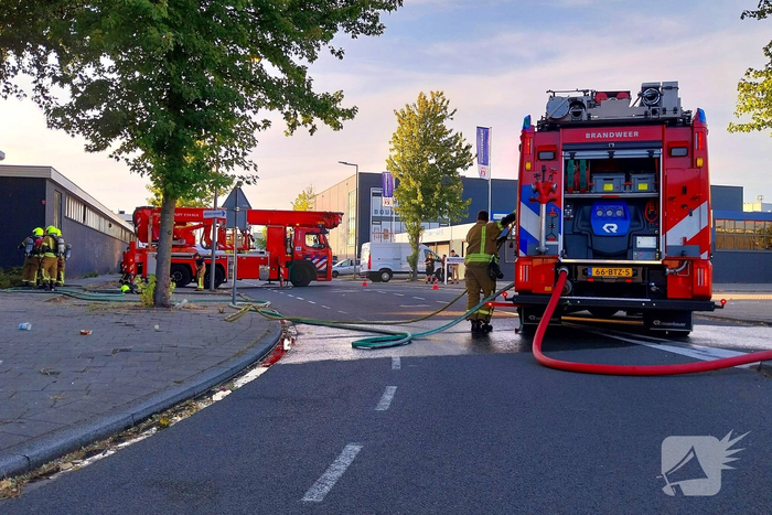 Brand in boom en bosschages naast bedrijfspand