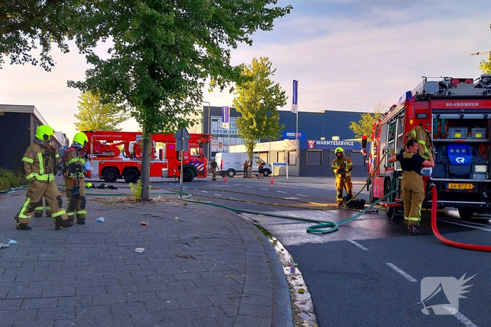 Brand in boom en bosschages naast bedrijfspand