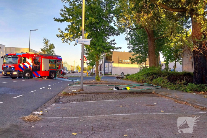 Brand in boom en bosschages naast bedrijfspand