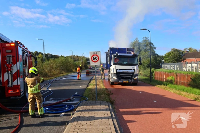 Grote afvalcontainer met huisvuil vat vlam tijdens rit