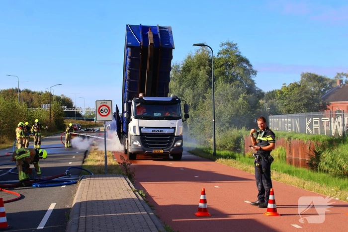 Grote afvalcontainer met huisvuil vat vlam tijdens rit
