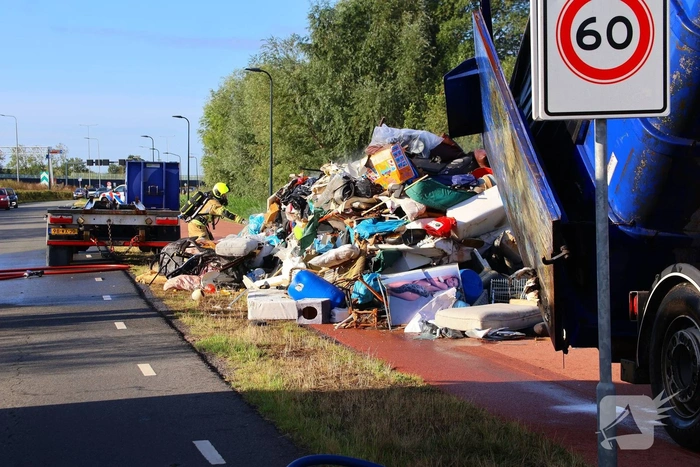 Grote afvalcontainer met huisvuil vat vlam tijdens rit