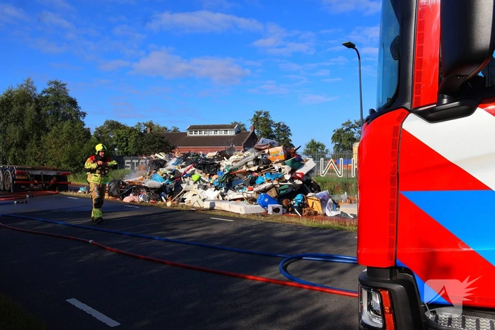Grote afvalcontainer met huisvuil vat vlam tijdens rit