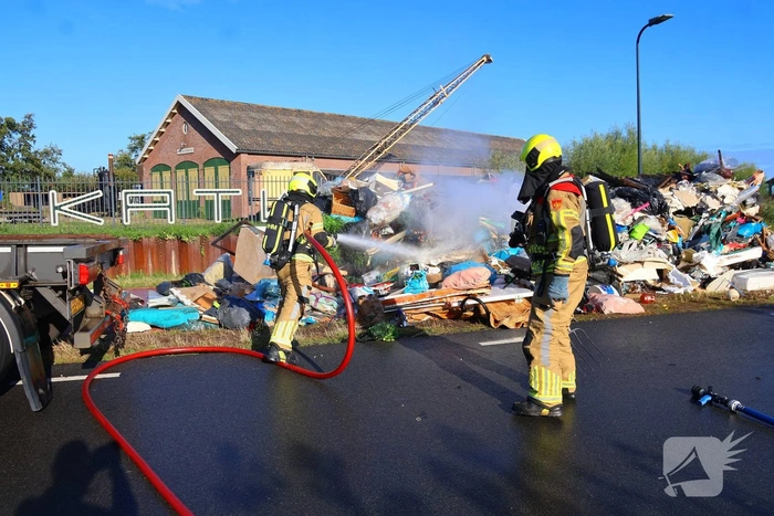 Grote afvalcontainer met huisvuil vat vlam tijdens rit