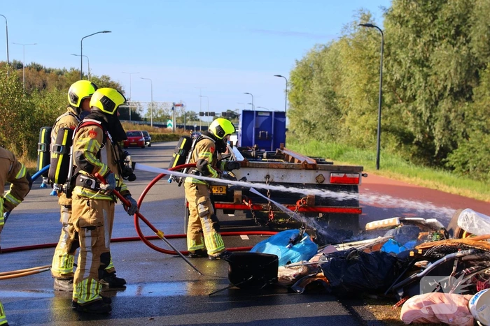 Grote afvalcontainer met huisvuil vat vlam tijdens rit