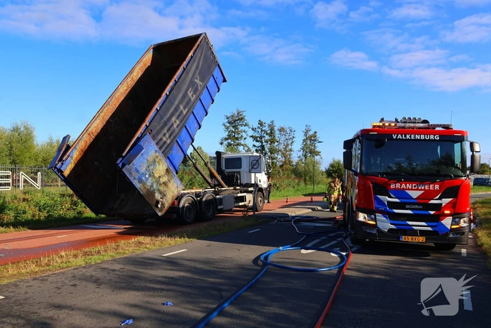 Grote afvalcontainer met huisvuil vat vlam tijdens rit
