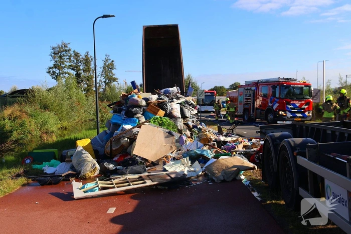 Grote afvalcontainer met huisvuil vat vlam tijdens rit