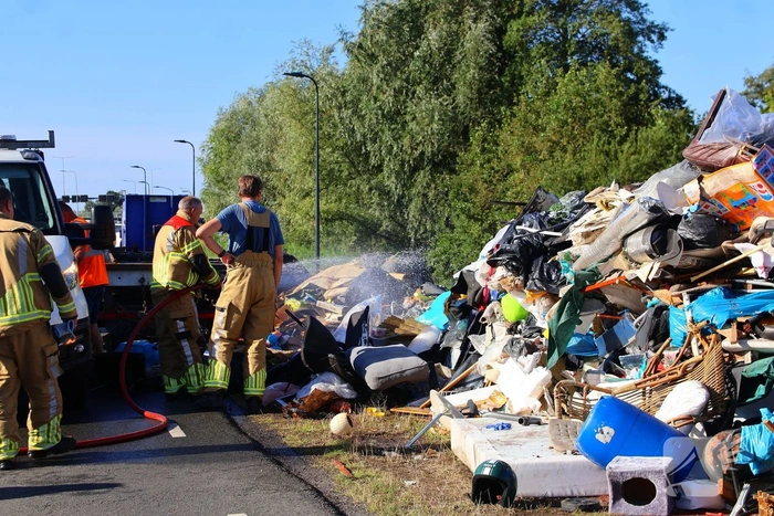 Grote afvalcontainer met huisvuil vat vlam tijdens rit
