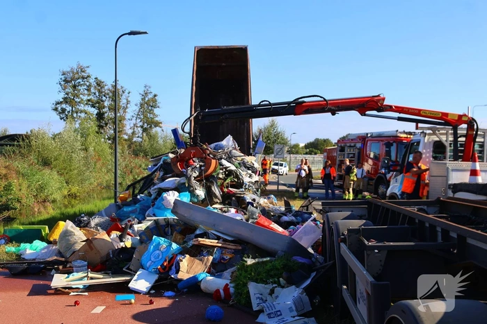 Grote afvalcontainer met huisvuil vat vlam tijdens rit