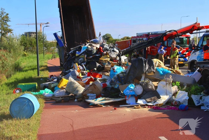 Grote afvalcontainer met huisvuil vat vlam tijdens rit