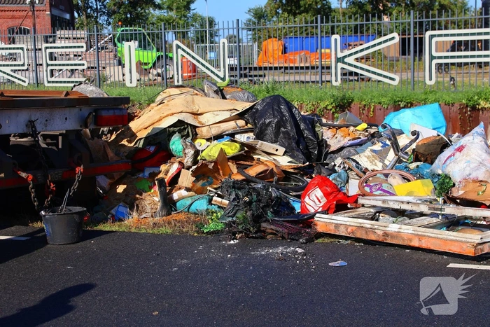 Grote afvalcontainer met huisvuil vat vlam tijdens rit