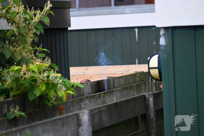 Brandweer blust brand tussen schutting en schuur