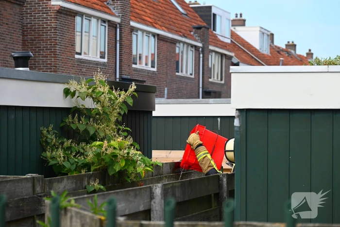 Brandweer blust brand tussen schutting en schuur