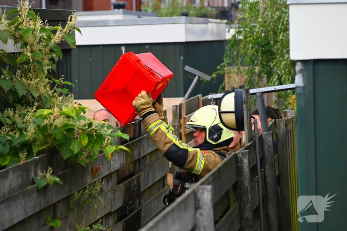 Brandweer blust brand tussen schutting en schuur