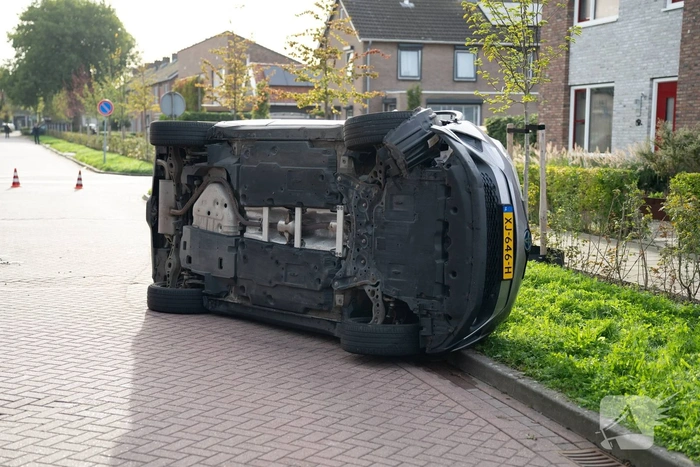 Auto op zijkant na botsing tegen geparkeerde auto