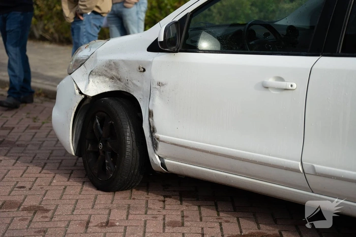 Auto op zijkant na botsing tegen geparkeerde auto
