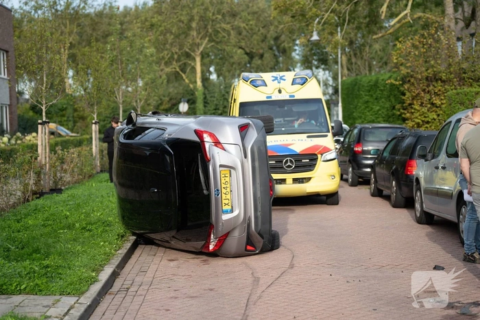 Auto op zijkant na botsing tegen geparkeerde auto