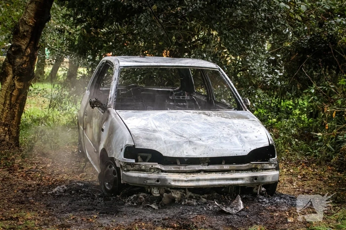 Personenauto volledig in brand tussen oude barakken