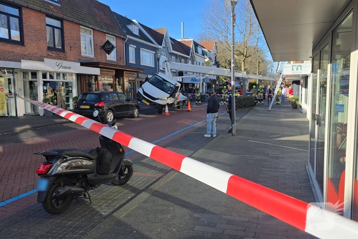 Hoogwerker kantelt tegen winkelpand