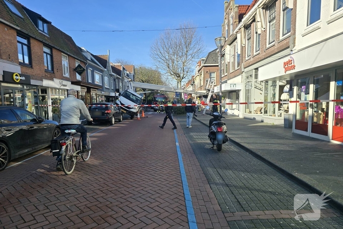 Hoogwerker kantelt tegen winkelpand