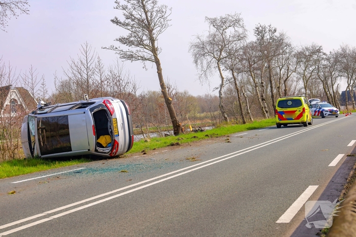 Auto belandt op zijn kant na botsing met boom