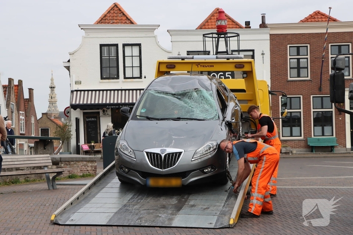 Auto op de kop op steiger na vergeten handrem