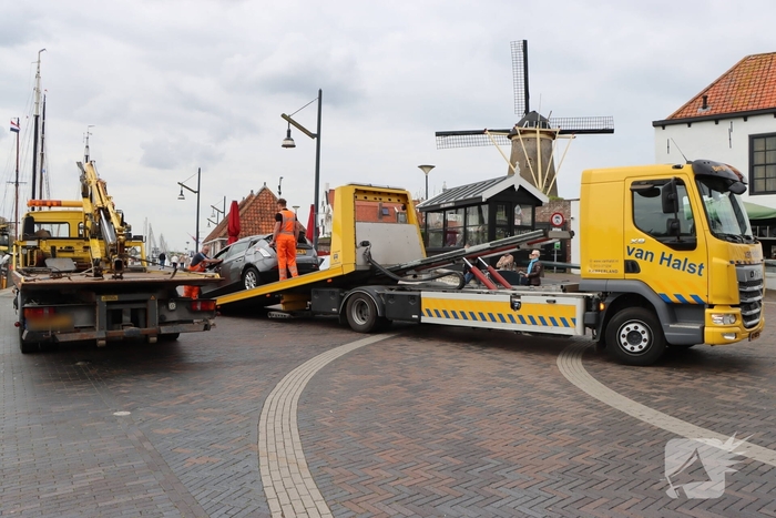 Auto op de kop op steiger na vergeten handrem
