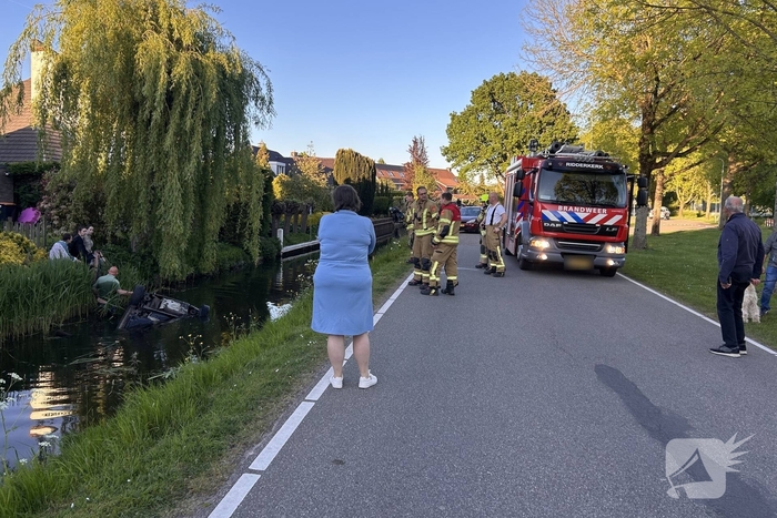 Auto belandt op de kop in het water, omstanders verrichten redding