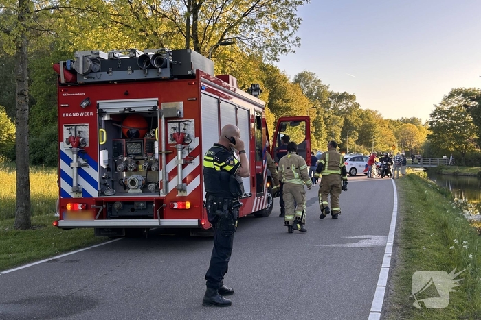 Auto belandt op de kop in het water, omstanders verrichten redding