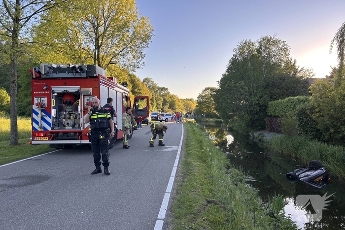 Auto belandt op de kop in het water, omstanders verrichten redding