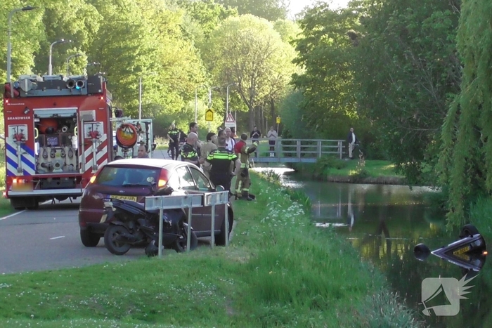 Auto belandt op de kop in het water, omstanders verrichten redding
