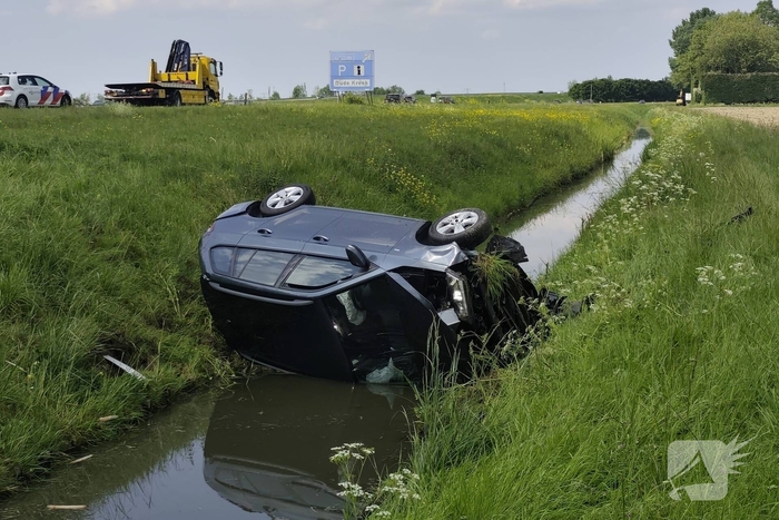 Auto belandt op zijkant in sloot naast snelweg
