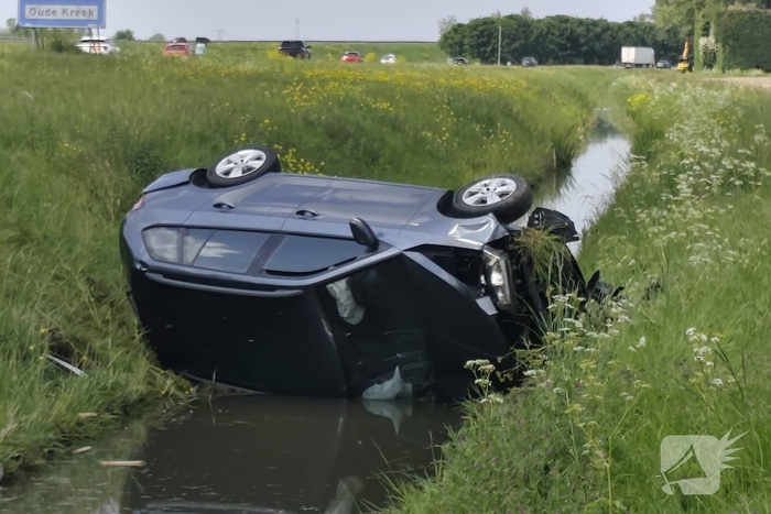 Auto belandt op zijkant in sloot naast snelweg