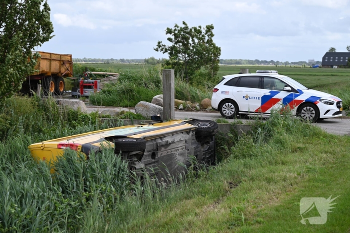 Bus van pakketdienst belandt op zijkant in sloot