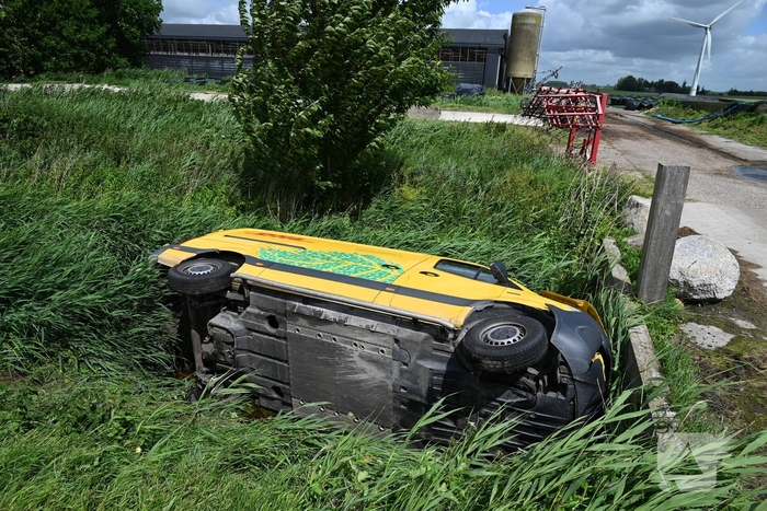 Bus van pakketdienst belandt op zijkant in sloot